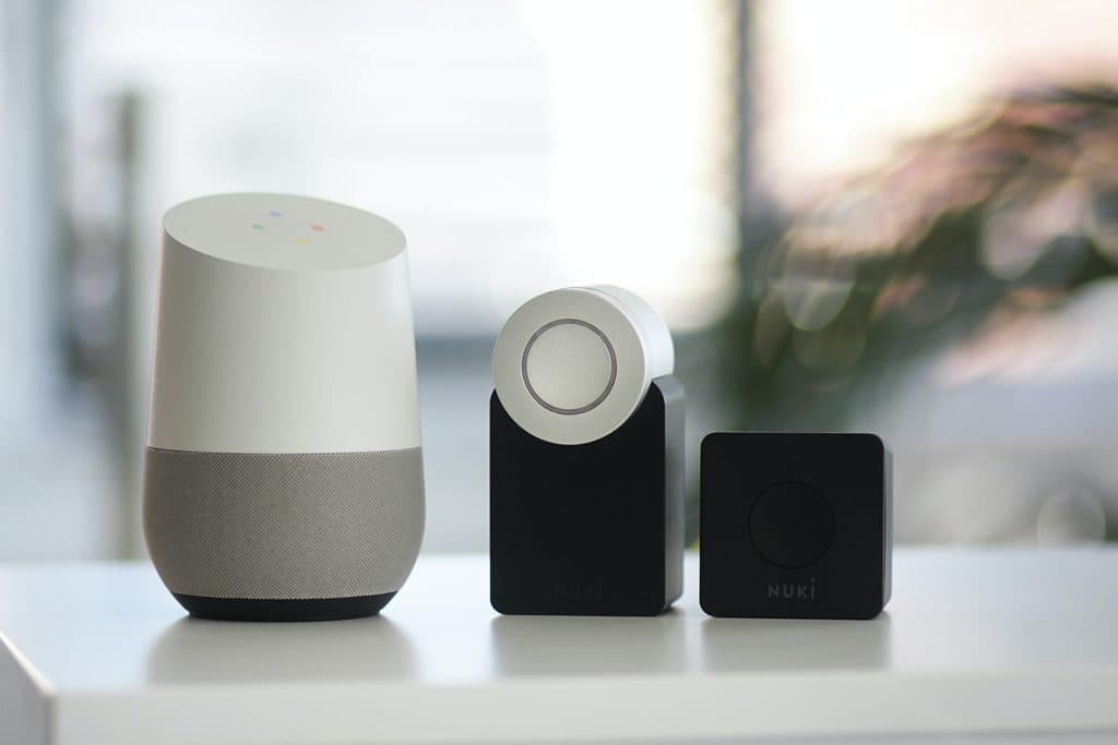 white and grey google smart speaker and two black smart speakers